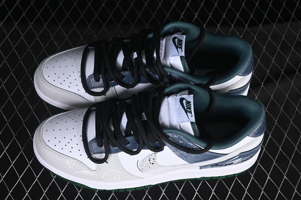 Top view of a pair of Nike SB Dunk Low sneakers showing perforated toe boxes, black laces, and dark green lining