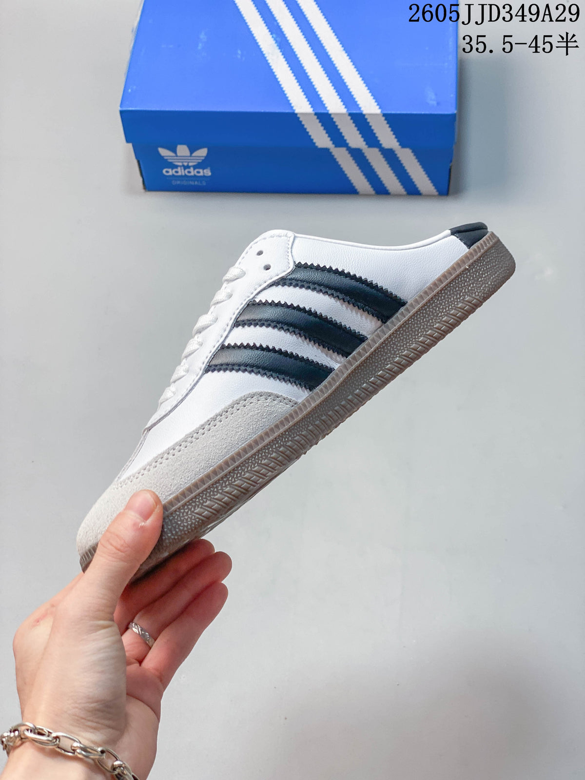 Side profile of a white mule sneaker with dark stripes and a gum-colored sole.