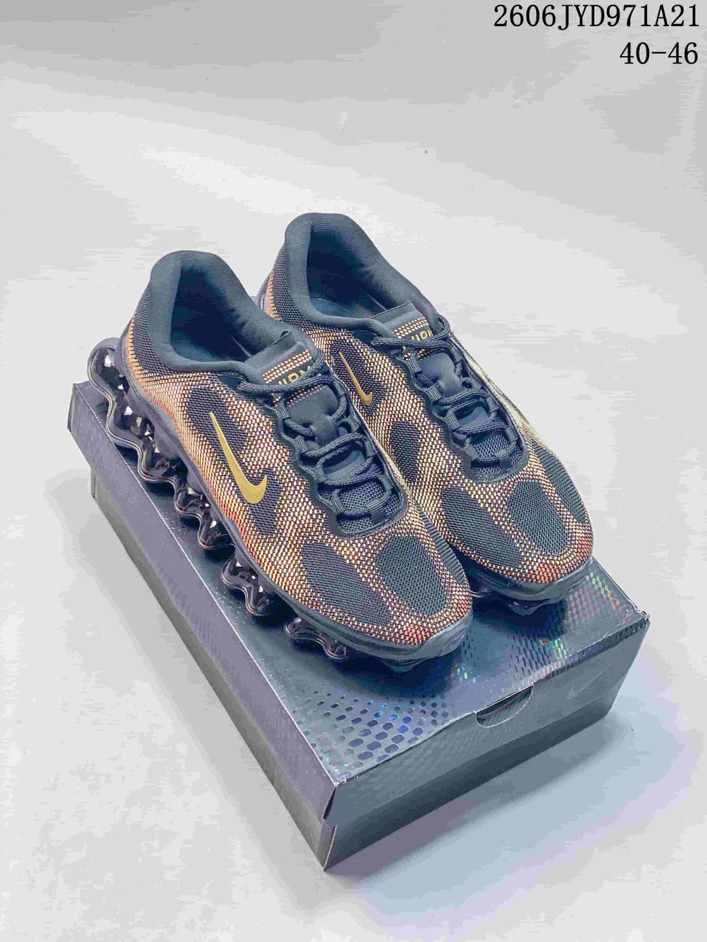 Nike Air Liquid Max shoes in a dark colorway with gold and orange accents, shown on a shoe box