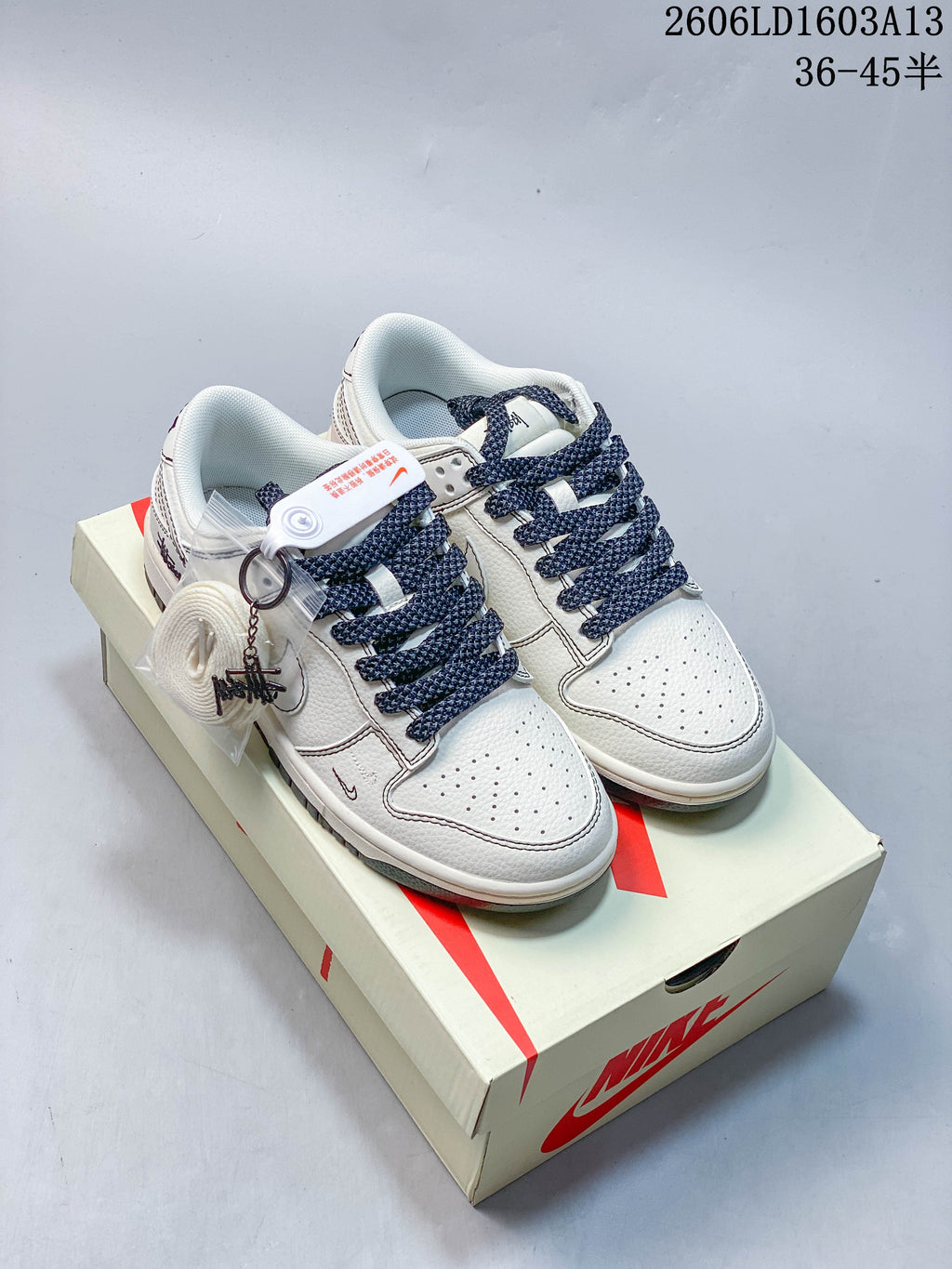Pair of white and navy low-top sneakers shown on a shoebox