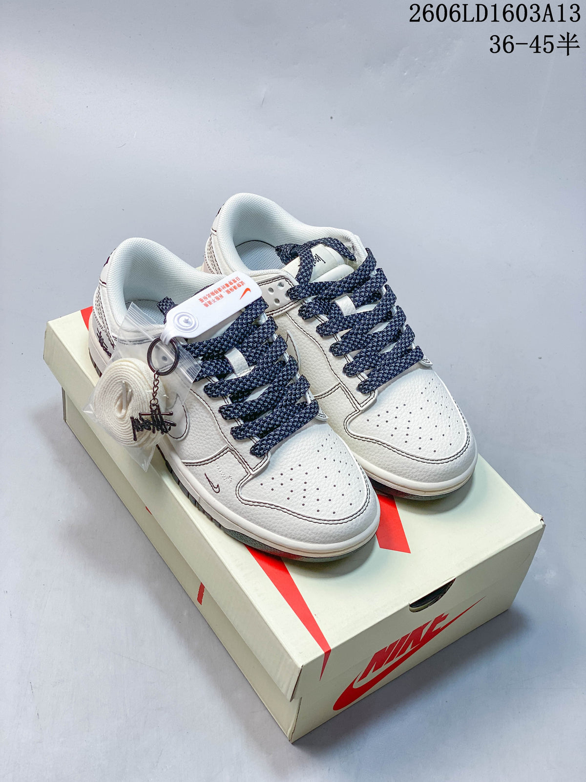 Pair of white and navy low-top sneakers shown on a shoebox