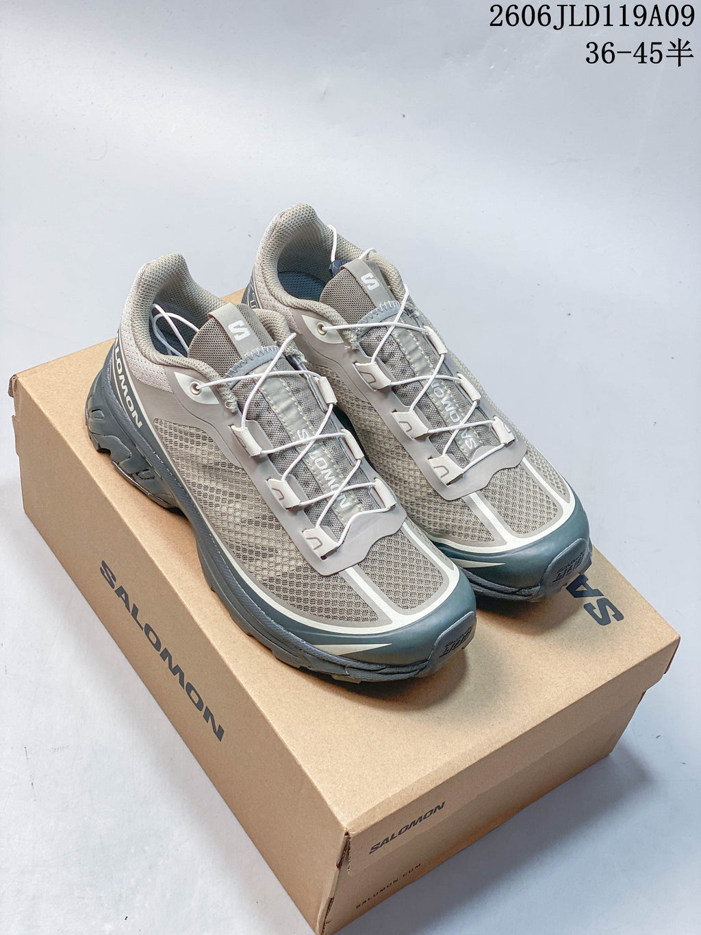 Pair of grey Salomon XT-6 FT shoes with quick laces and blue-green accents, displayed on a shoe box.