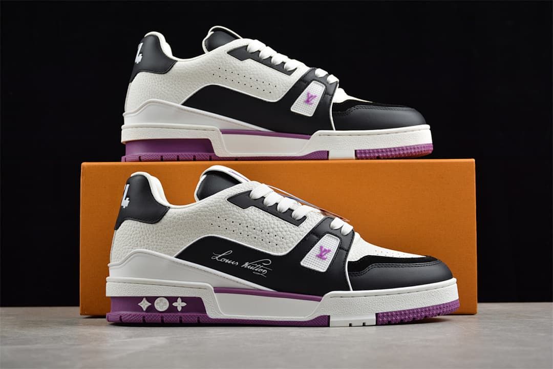Two sneakers displayed on an orange box, showing their white, black, and purple design