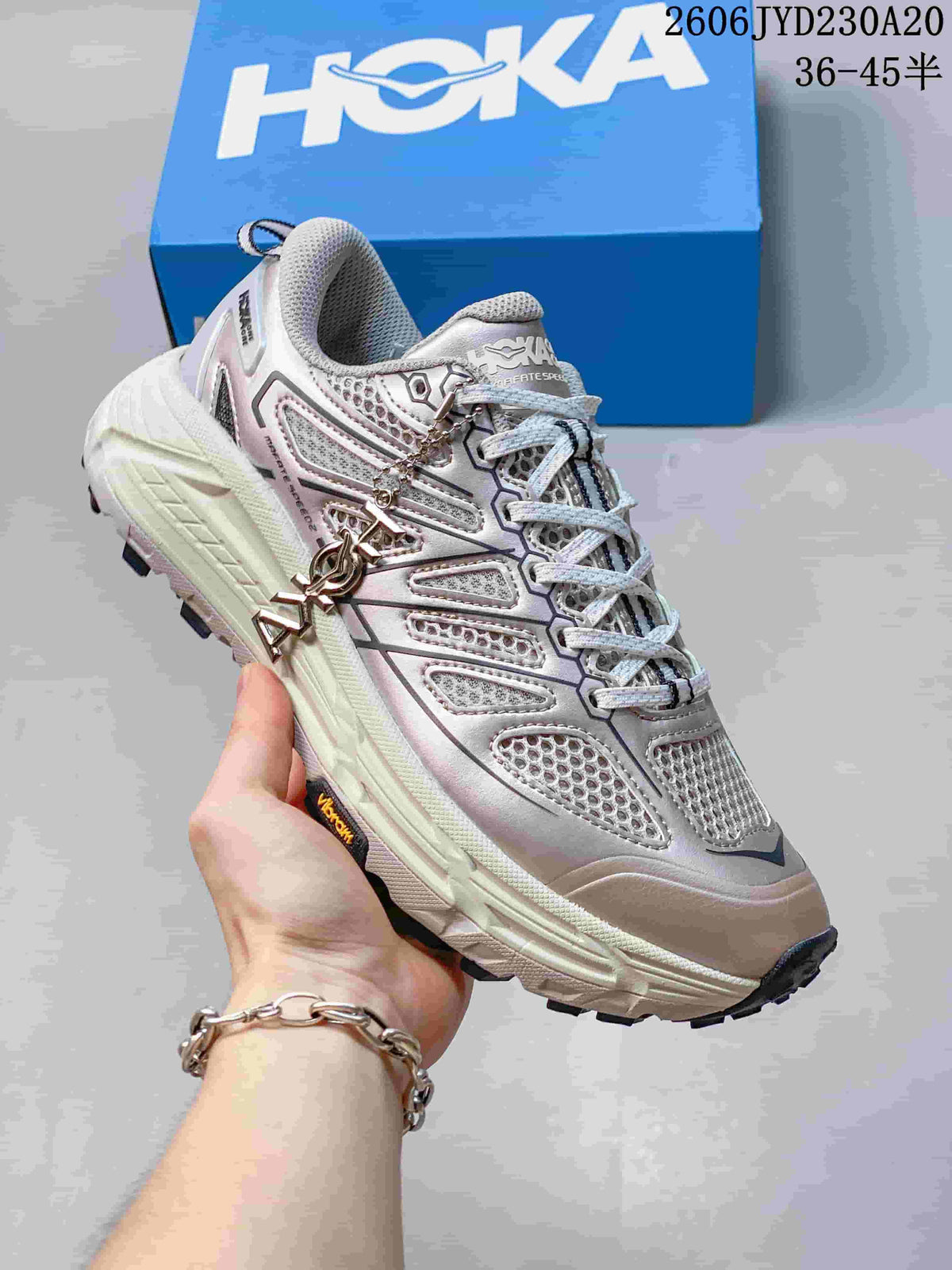 Angled view of a silver-toned running shoe with dark detailing and a lugged outsole