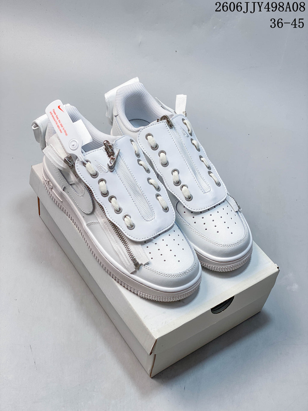 Pair of white low-top Nike Air Force 1 ’07 sneakers with layered lace covers, zip details, and perforated toe boxes.