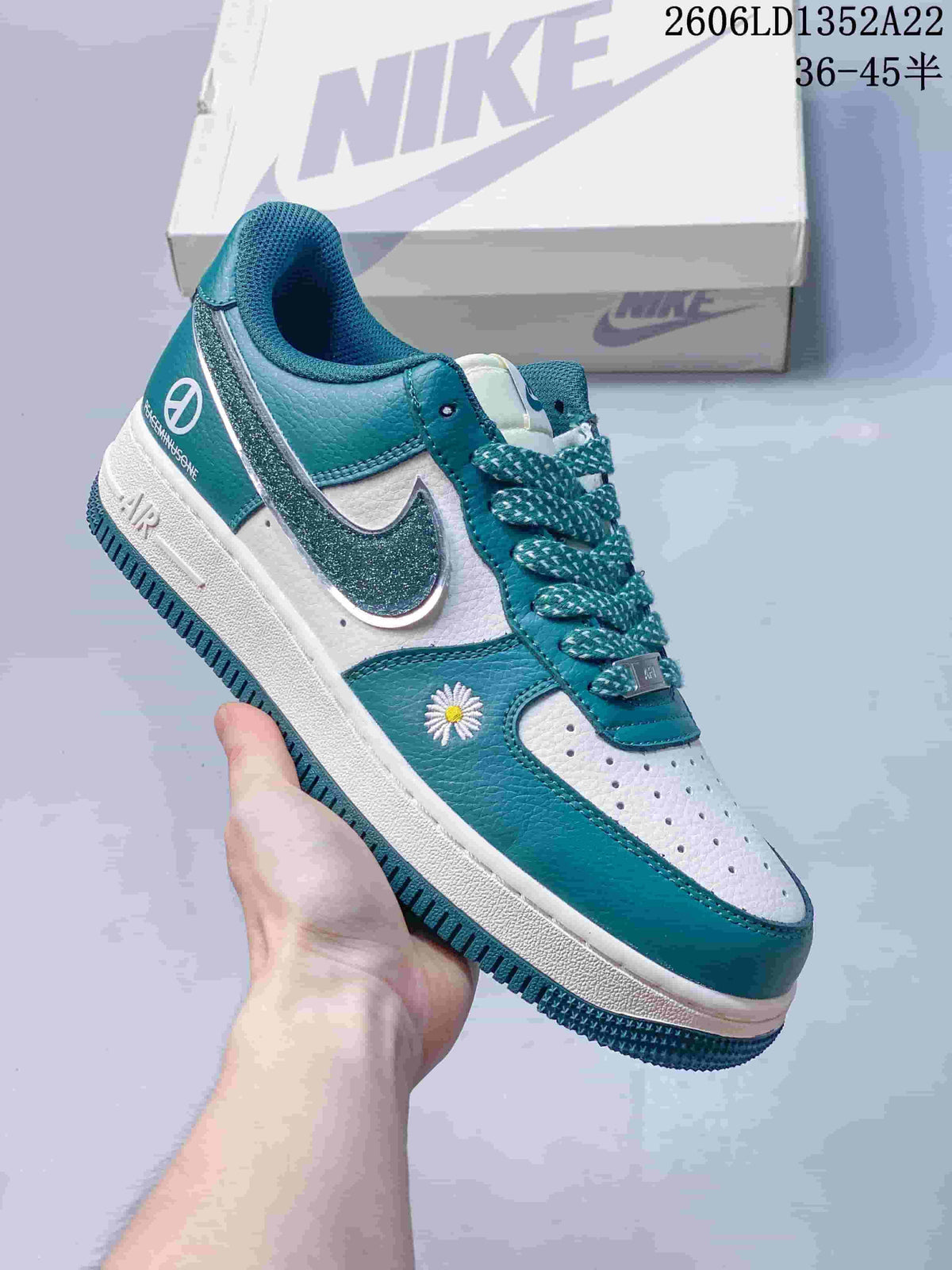 Teal and white low-top sneaker with patterned laces, glitter-effect Swoosh and daisy embroidery.
