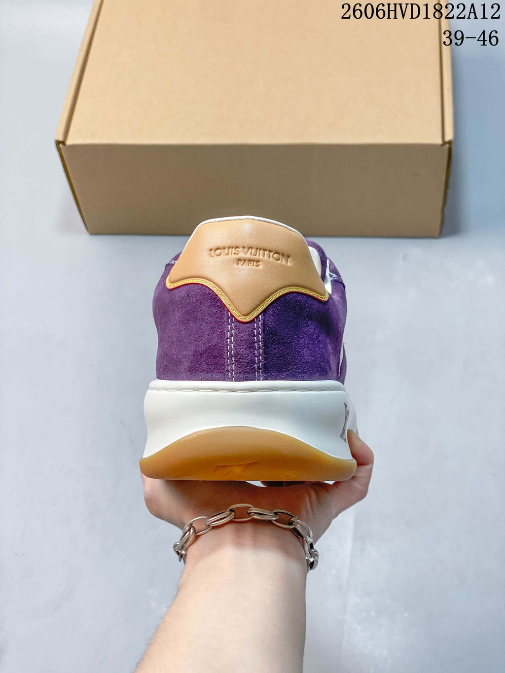 Rear view of a purple sneaker with a tan heel tab and white midsole.