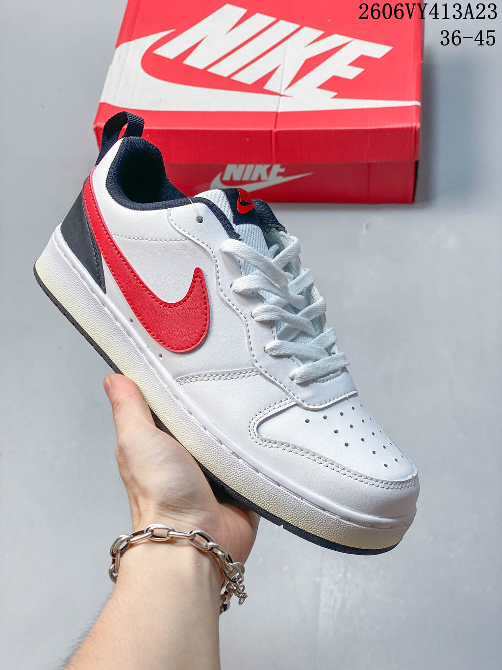 White sneaker with a red Swoosh, dark heel panel, and navy collar