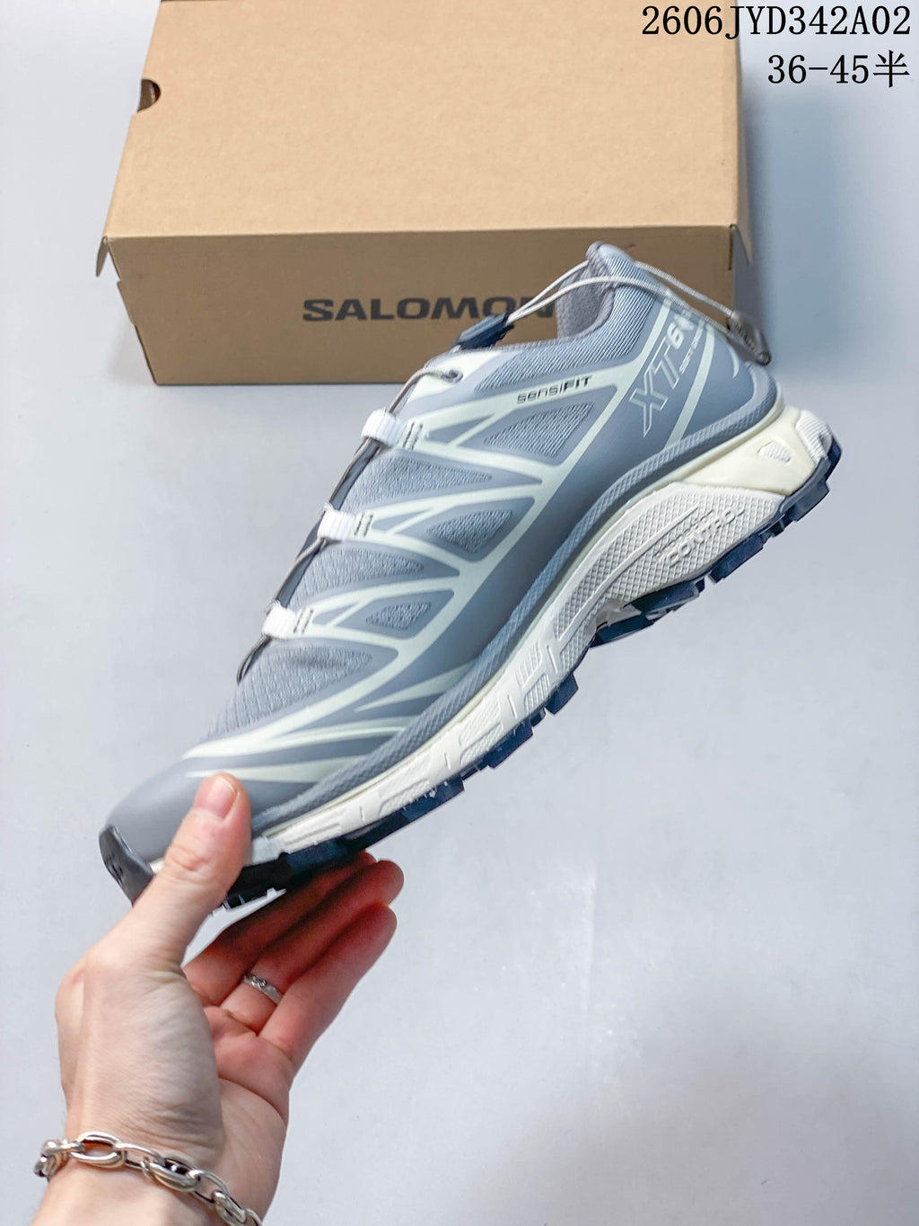 Side profile of a gray Salomon trail running shoe with light overlays and a lugged sole