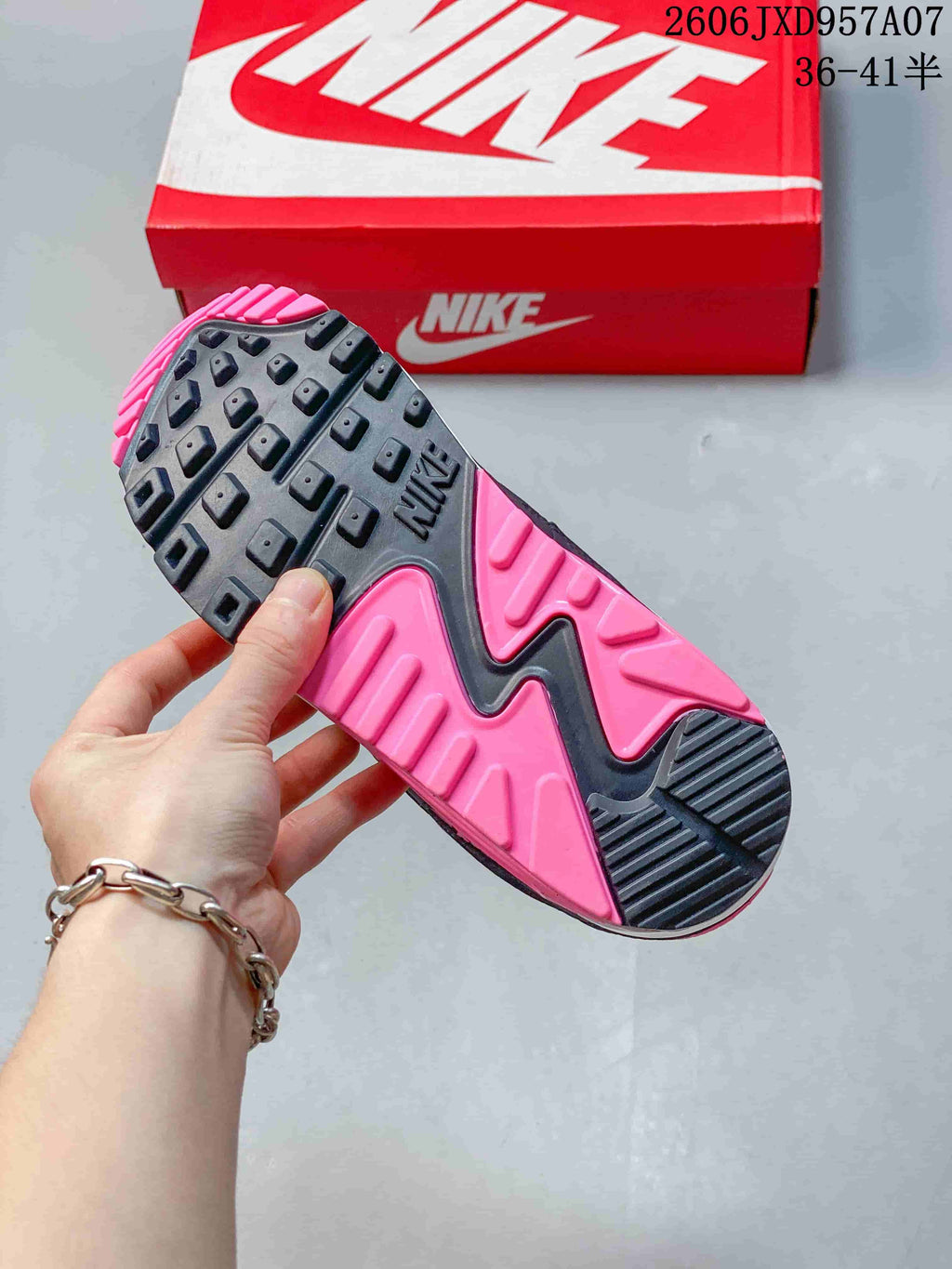 Close-up of the pink and dark textured outsole of a Nike Air Max 90 sneaker