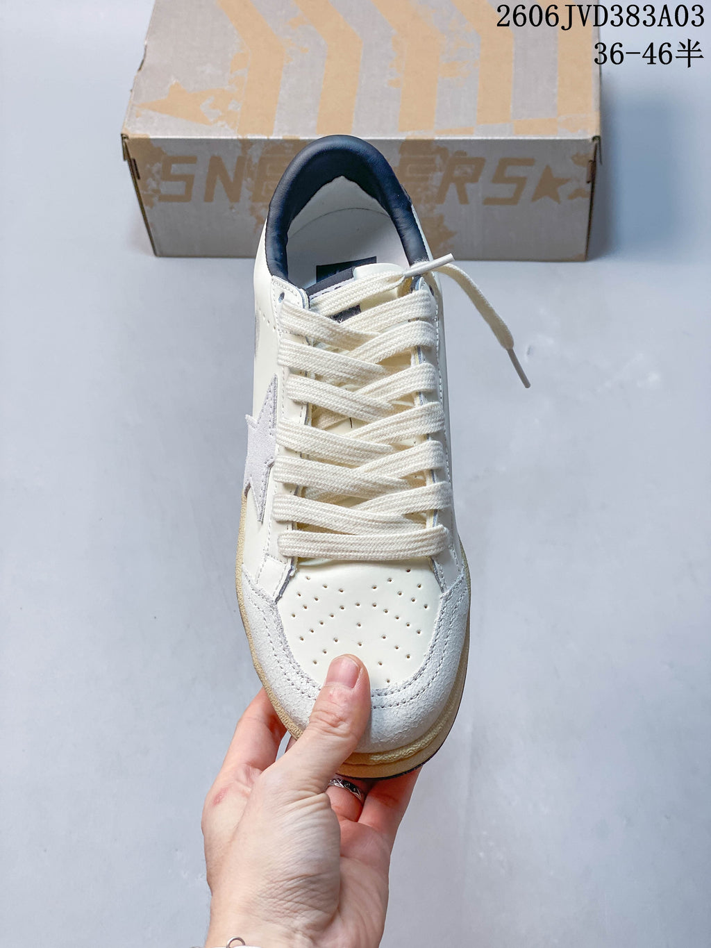 Top view of off-white lace-up sneaker with perforated toe and side star