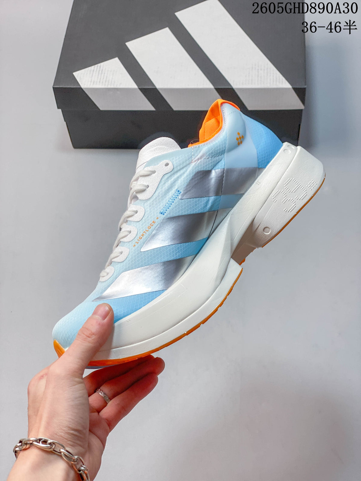 Side view of the shoe showing silver stripes, pale blue panels, and a white sole