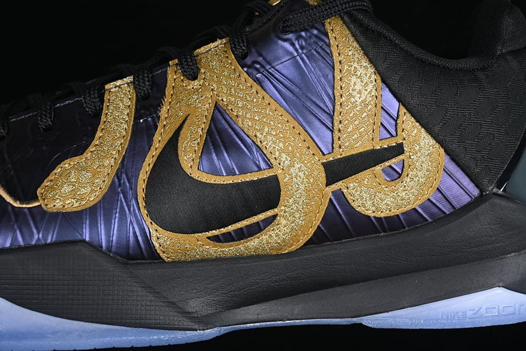 Close-up of gold side detailing over a purple and black upper