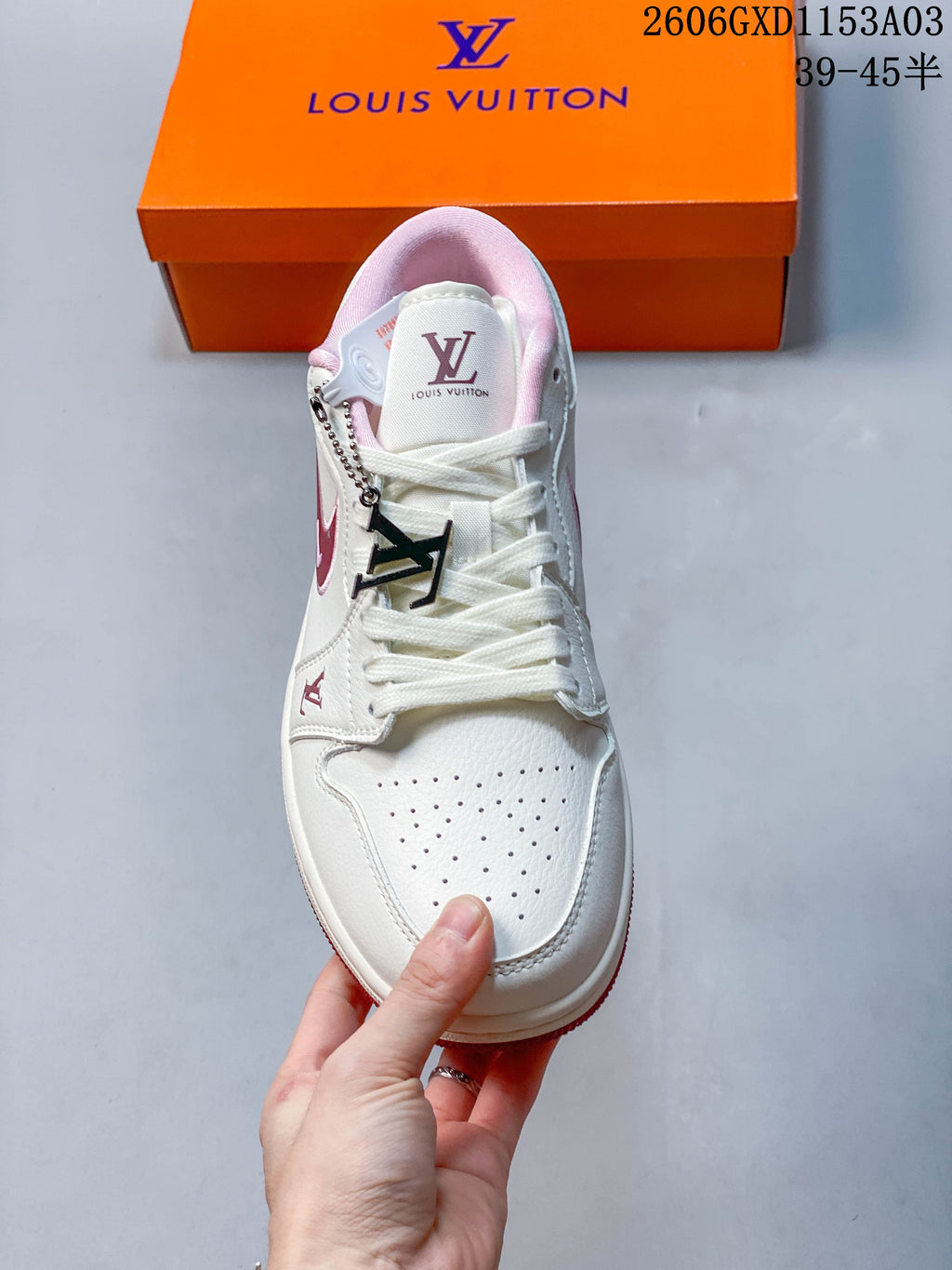 Top view showing the perforated toe, pink lining, laces, and decorative metal charm.