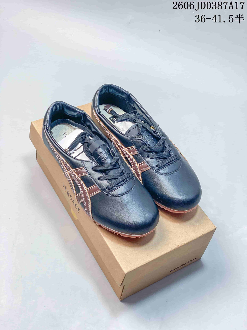 Pair of dark navy and brown low-top lace-up sneakers displayed on a branded box