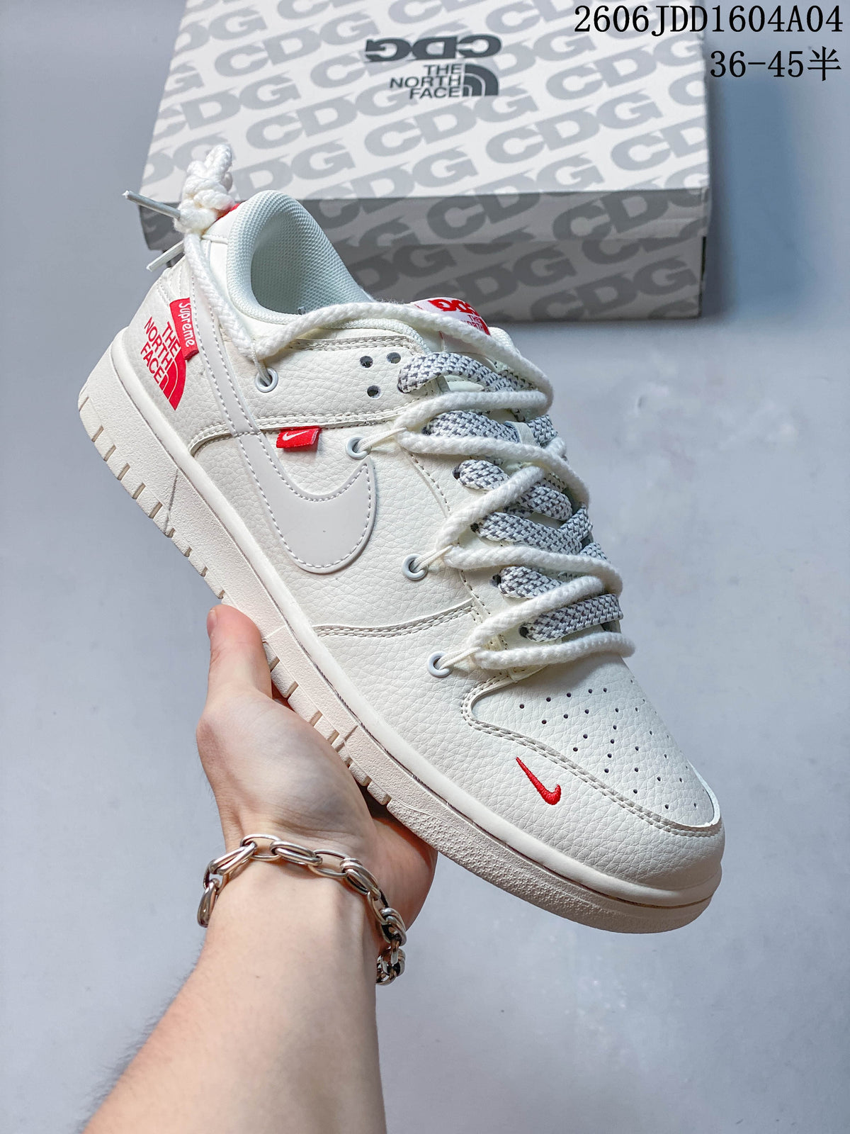 White low-top sneaker with red accents and thick white laces, shown beside a branded box.