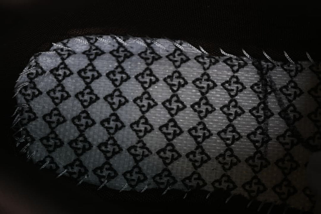 Close-up of a patterned insert or lining piece beside the boot.