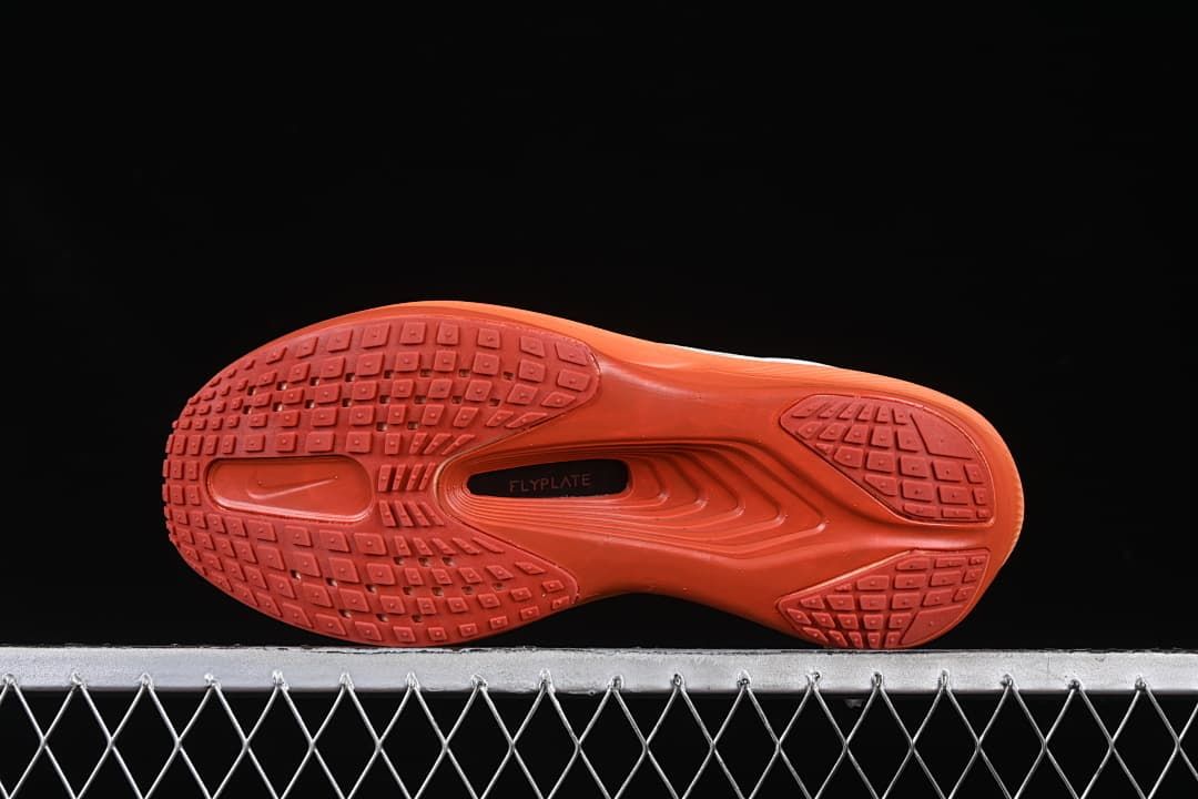 Underside of the shoe with coral-orange tread and central plate detail
