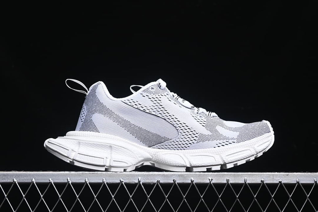 Side profile of the white sneaker with a sculpted chunky sole.