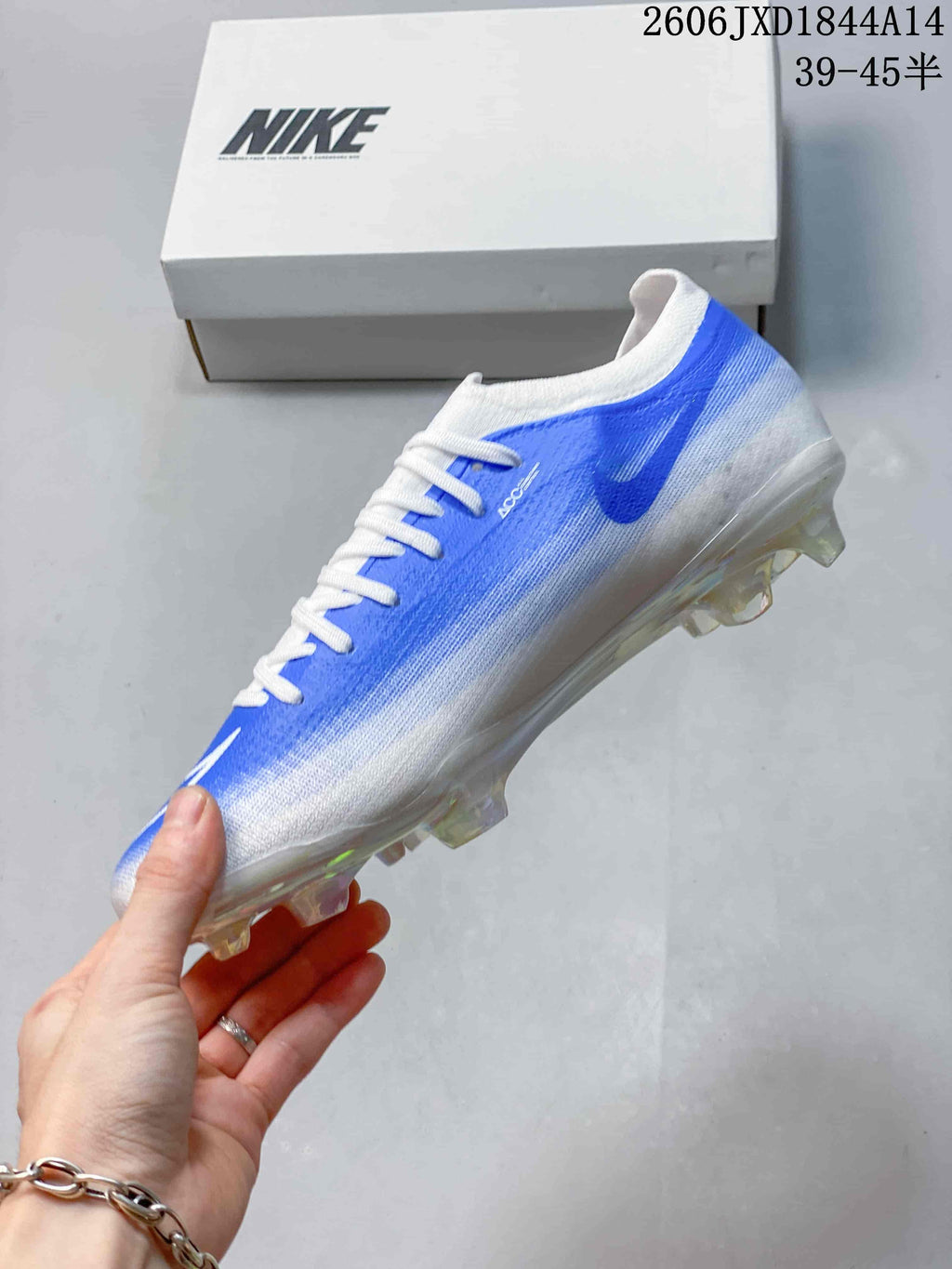 Side view of a blue-and-white Nike soccer cleat with a studded outsole.