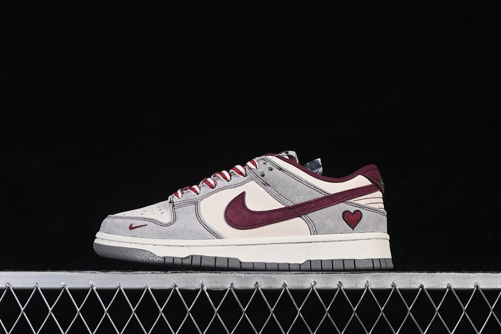 Side view of a gray and off-white low-top sneaker with a burgundy swoosh and heart detail at the heel