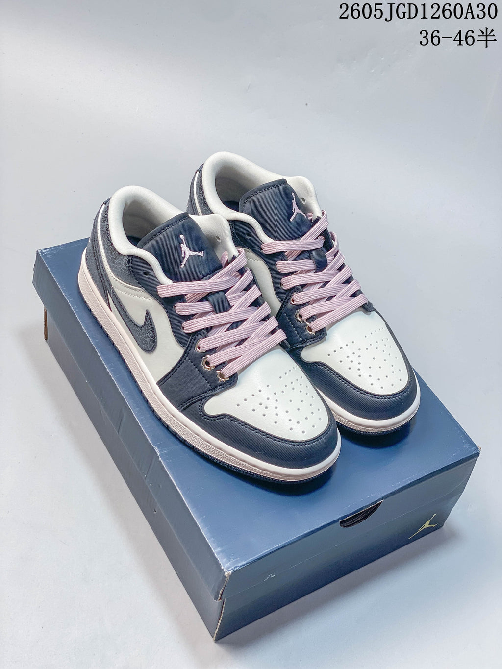 Pair of navy, white and pink Air Jordan 1 Low sneakers on a shoebox