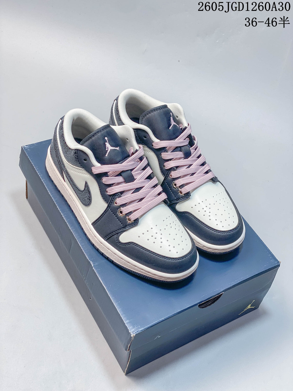 Pair of navy, white and pink Air Jordan 1 Low sneakers on a shoebox