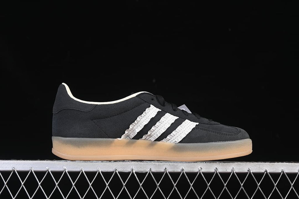Side profile of a black low-top sneaker with white stripes and gum-colored outsole.