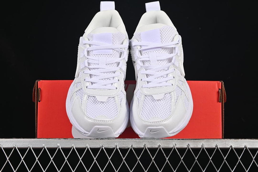Front view of the white sneakers displayed on a red box