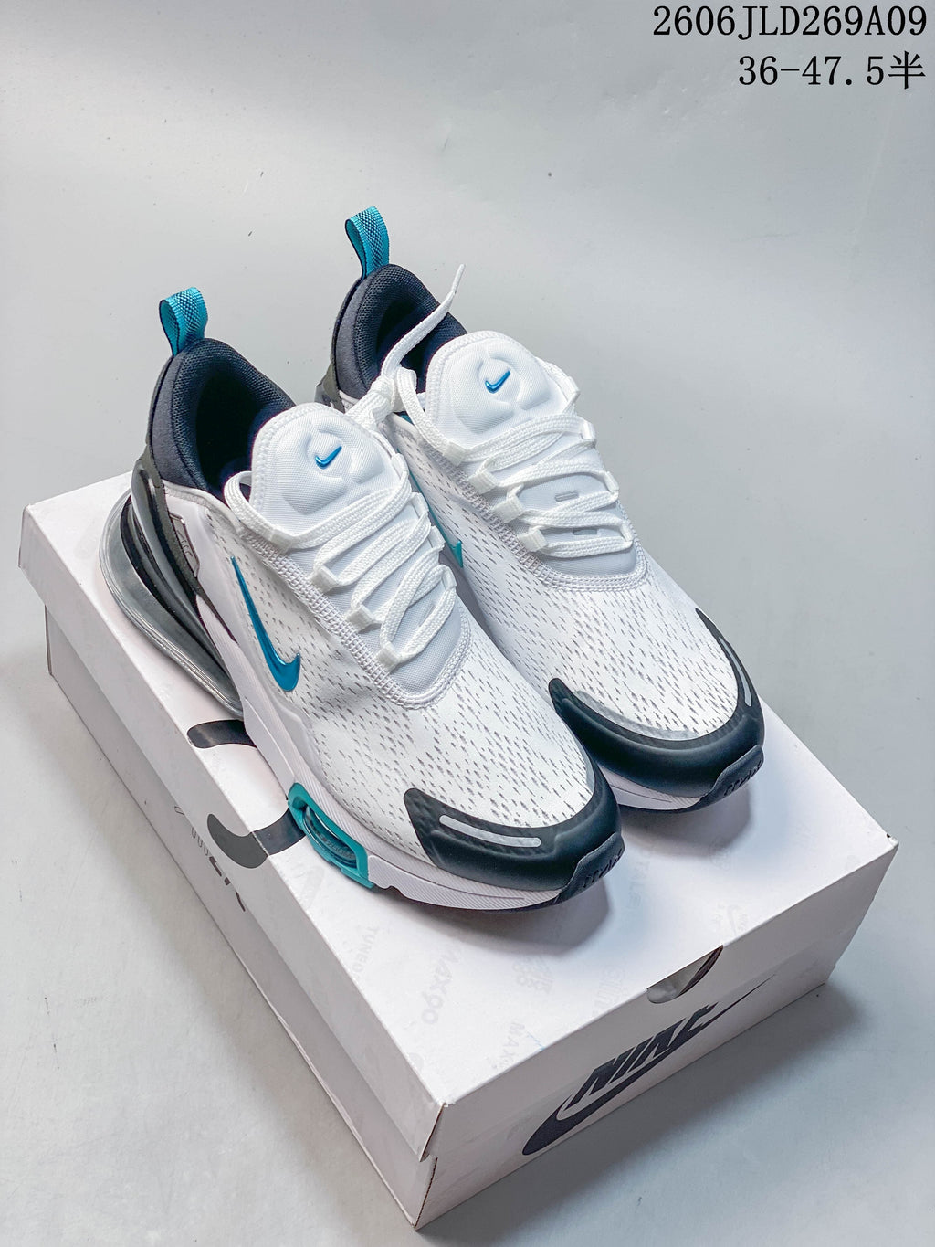 Pair of white Nike Air Max 270 sneakers with teal and dark accents displayed on a shoe box