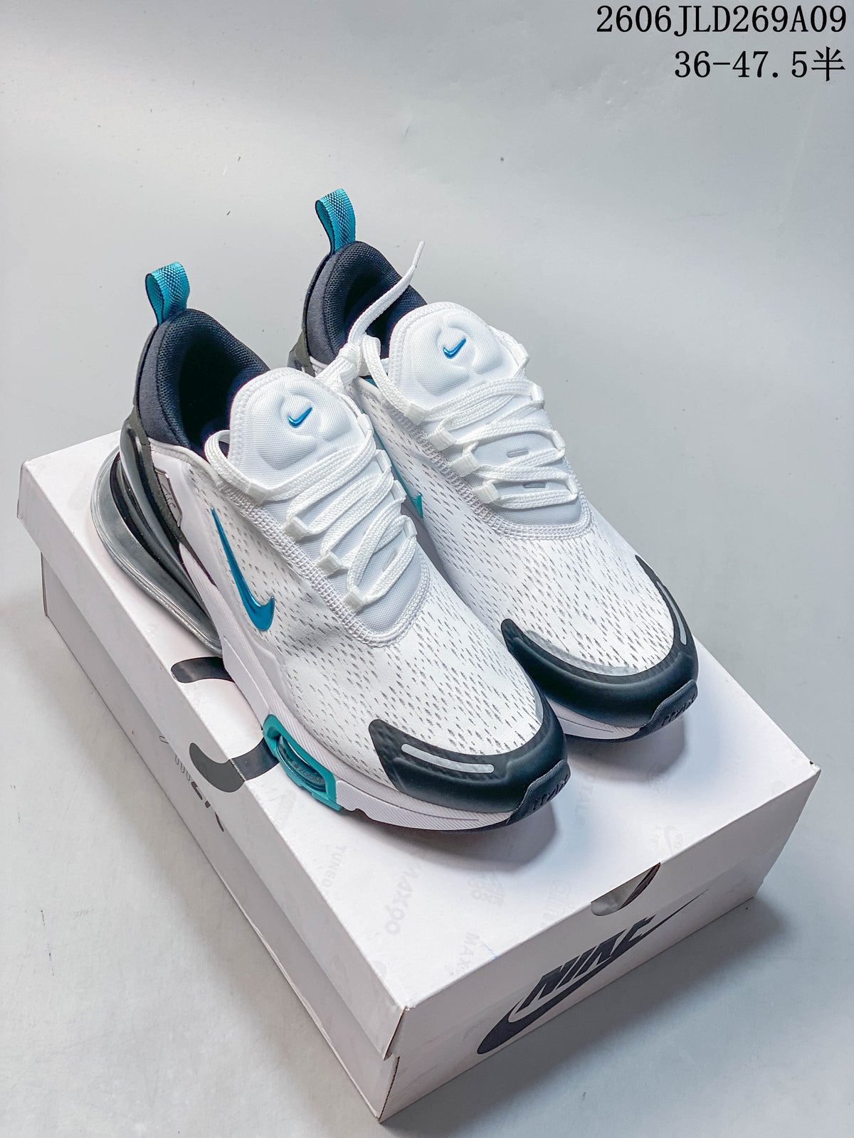 Pair of white Nike Air Max 270 sneakers with teal and dark accents displayed on a shoe box