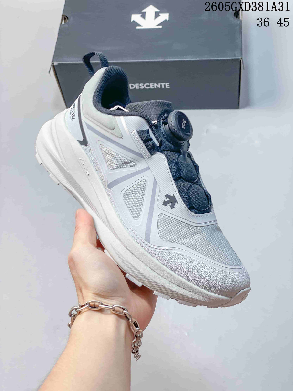 Angled side view of a white and gray Descente sneaker with a dial closure