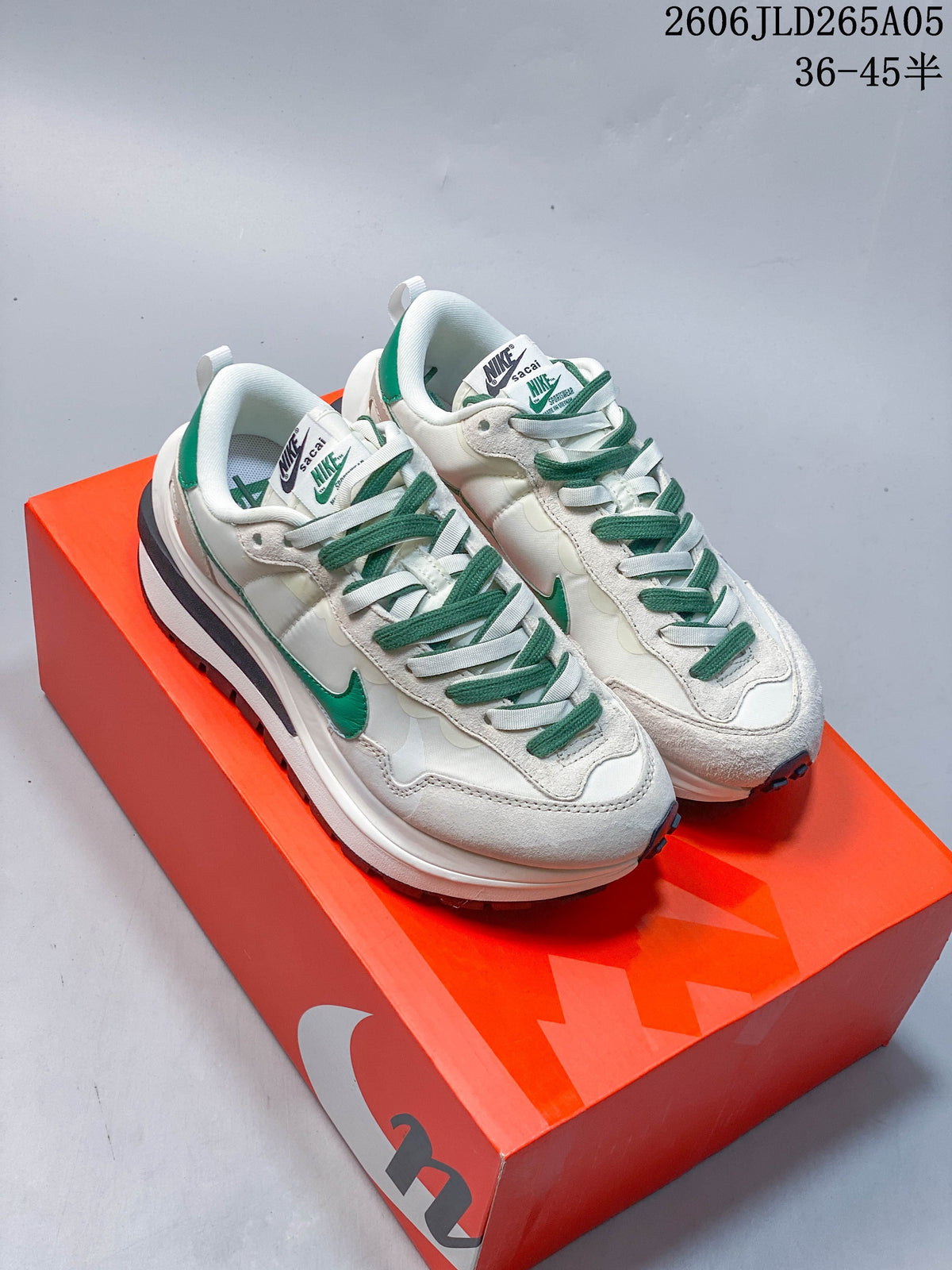 Pair of off-white and green Nike x sacai LDWaffle sneakers shown from above on an orange shoe box.