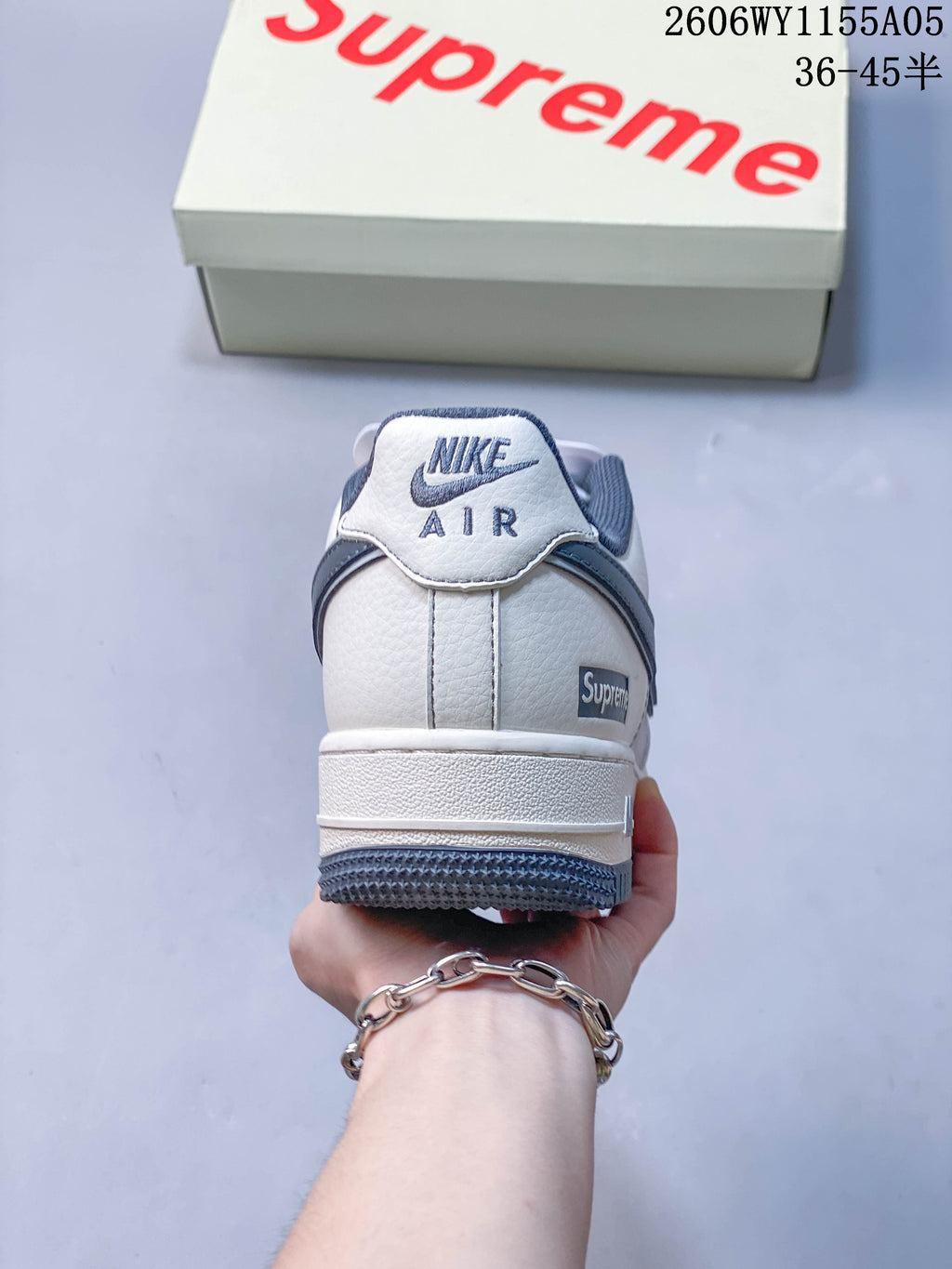 Rear view of a white and slate-blue low-top sneaker with Supreme branding