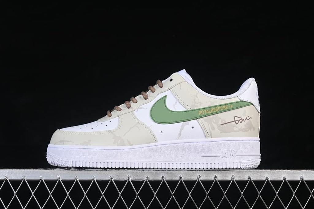 Side view of a white and cream Nike Air Force 1 '07 Low with a green side accent and brown laces