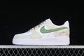 Side view of a white and cream Nike Air Force 1 '07 Low with a green side accent and brown laces