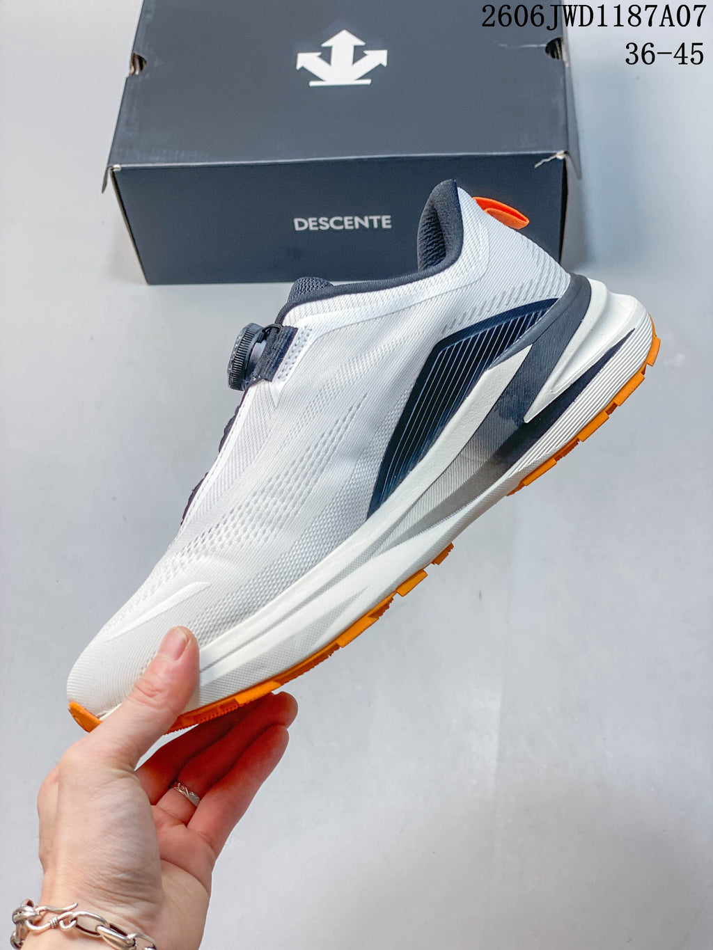Side profile of the white trail-running shoe with navy detailing and orange outsole