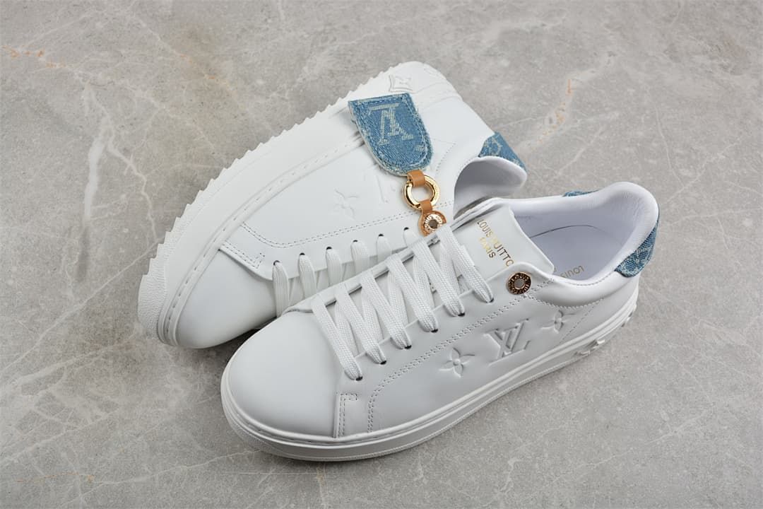Pair of white low-top platform sneakers with blue accents and embossed side motifs