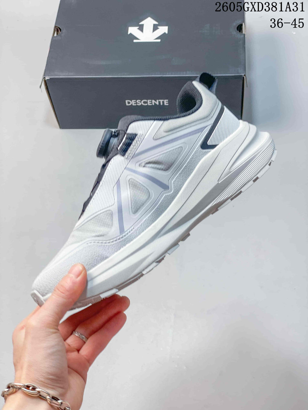 Side view of a white and gray Descente sneaker with a thick sole