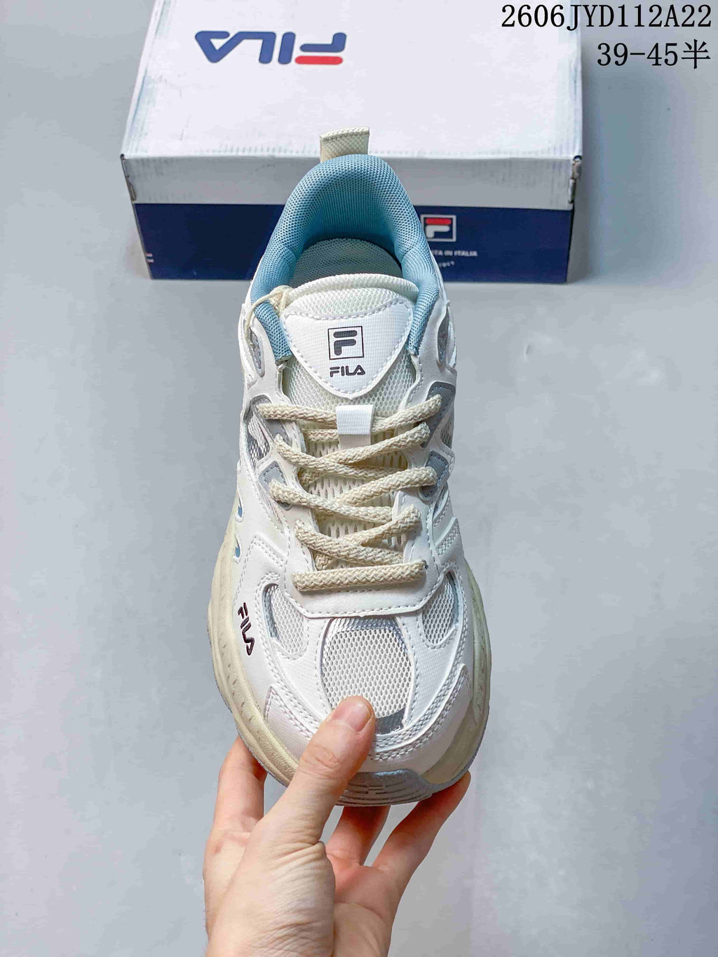 Front view of a white FILA sneaker with mesh panels, blue lining, and cream laces.