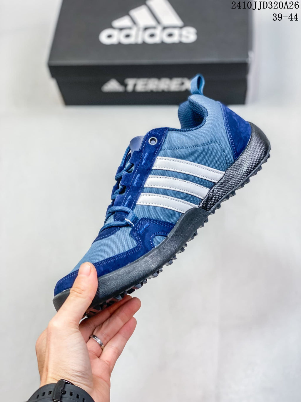 Side view of the blue adidas Daroga Plus Canvas shoe with white stripes and a lugged outsole.