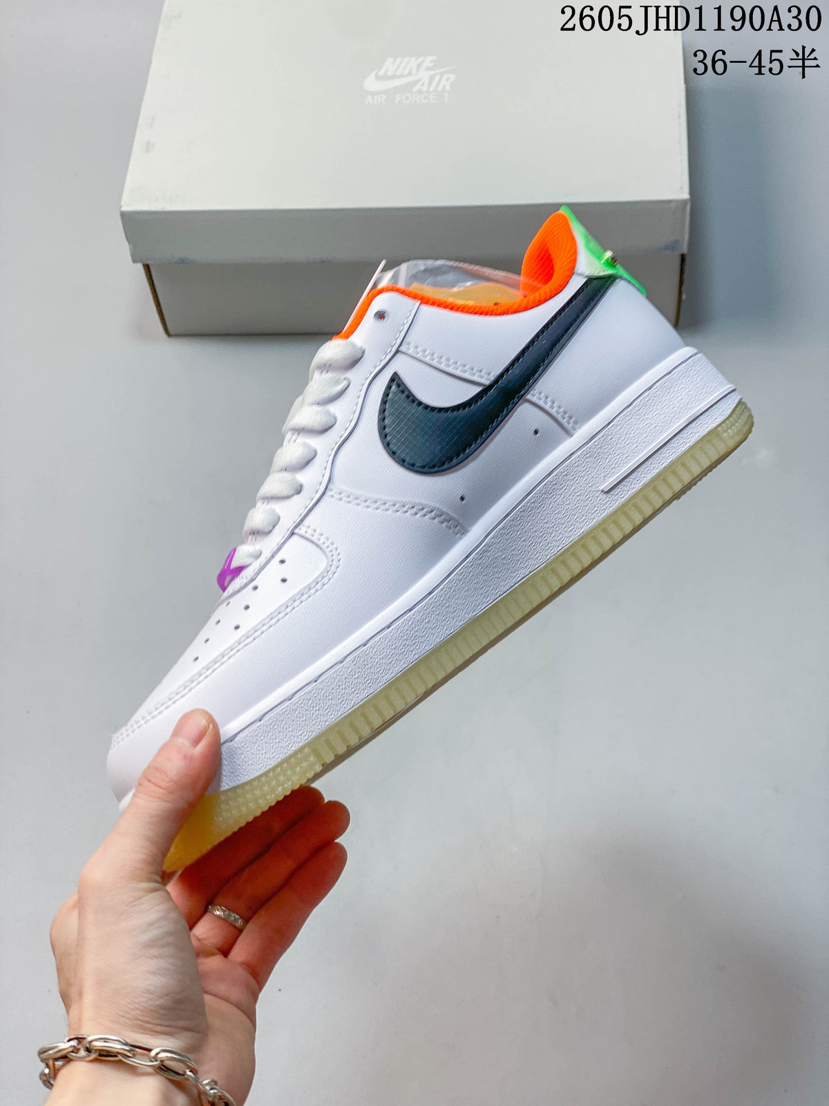 Side view of the white low-top sneaker with dark patterned side panel, green trim, orange lining, and translucent outsole