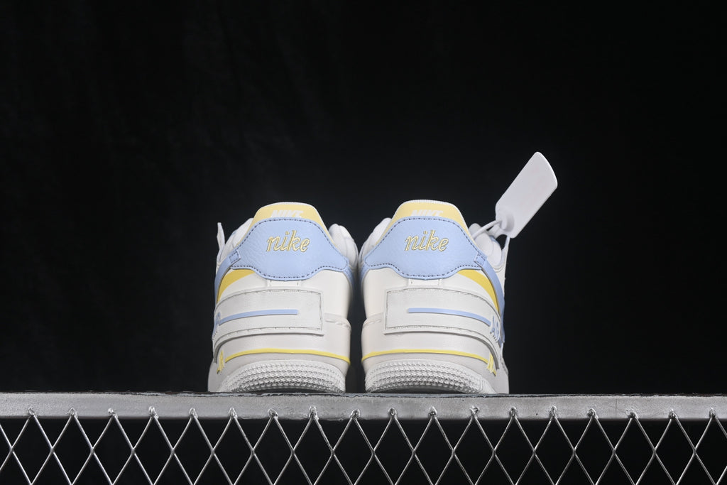 Rear view of the pair showing light blue heel panels, yellow accents, layered heel construction, and textured outsoles.