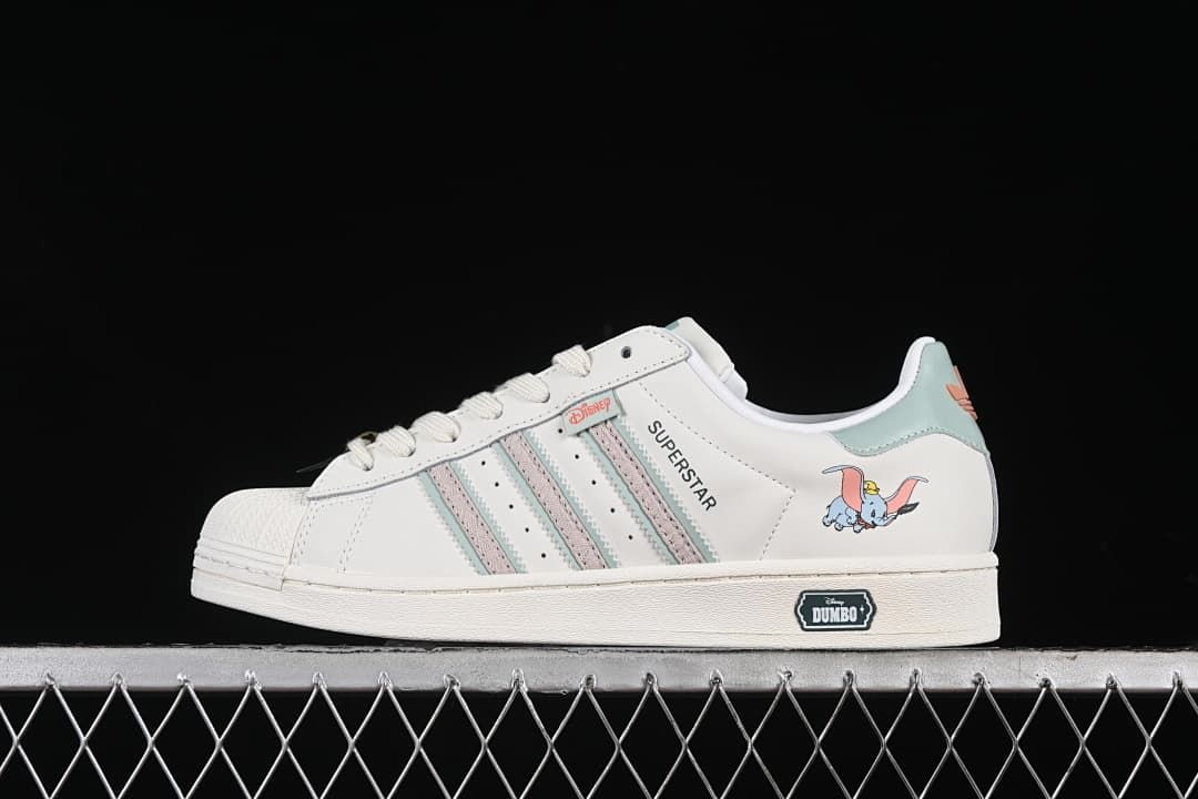 Side view of white adidas Superstar IE5880 Dumbo sneakers with pale aqua and pink accents