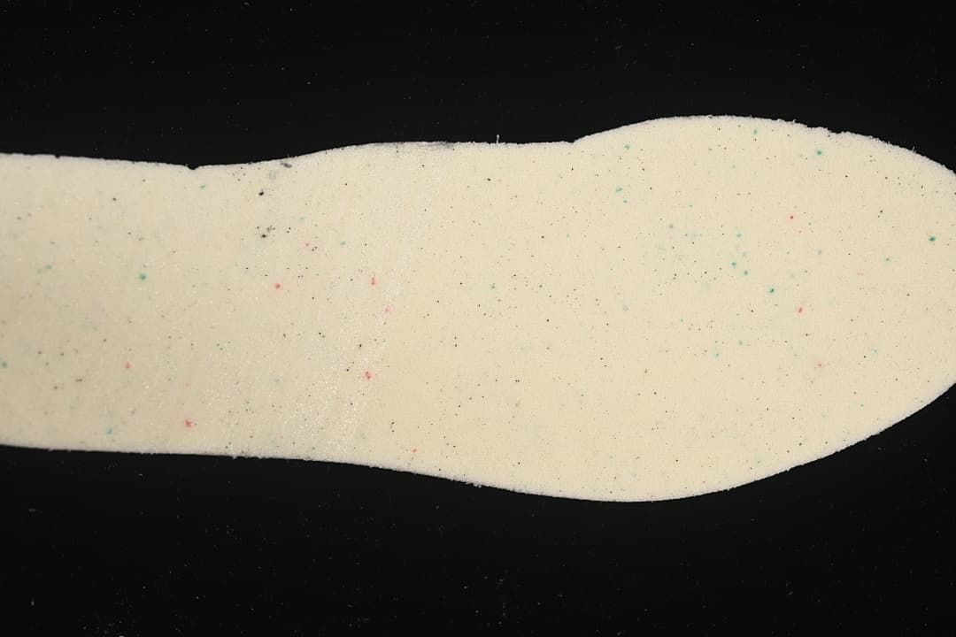 Close-up view of a light-colored shoe insert with small colored flecks.