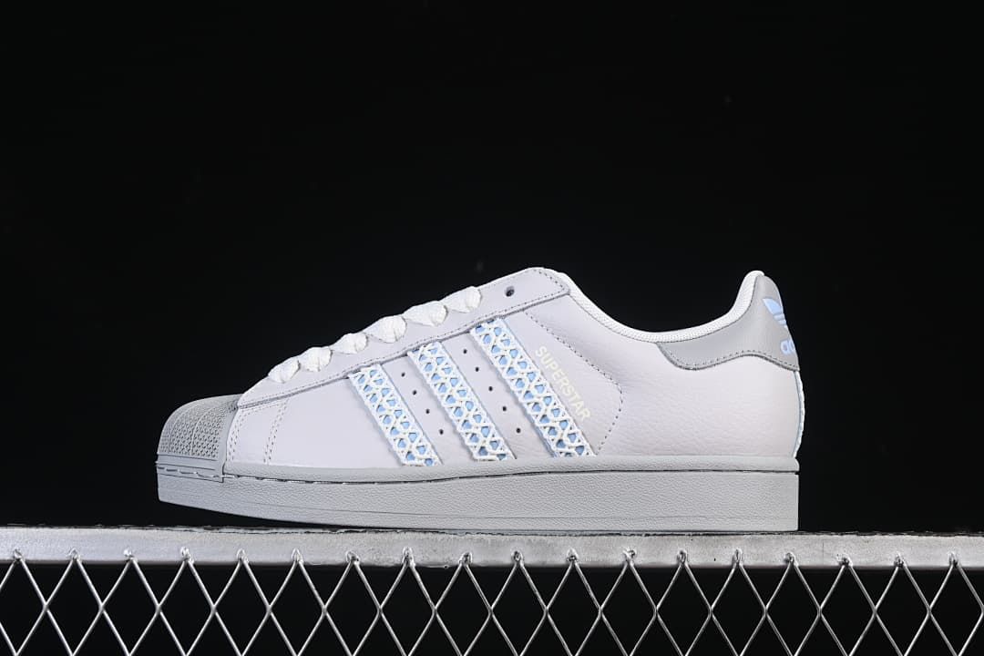 Side view of a white adidas Superstar II sneaker with pale blue patterned stripes and a grey sole.