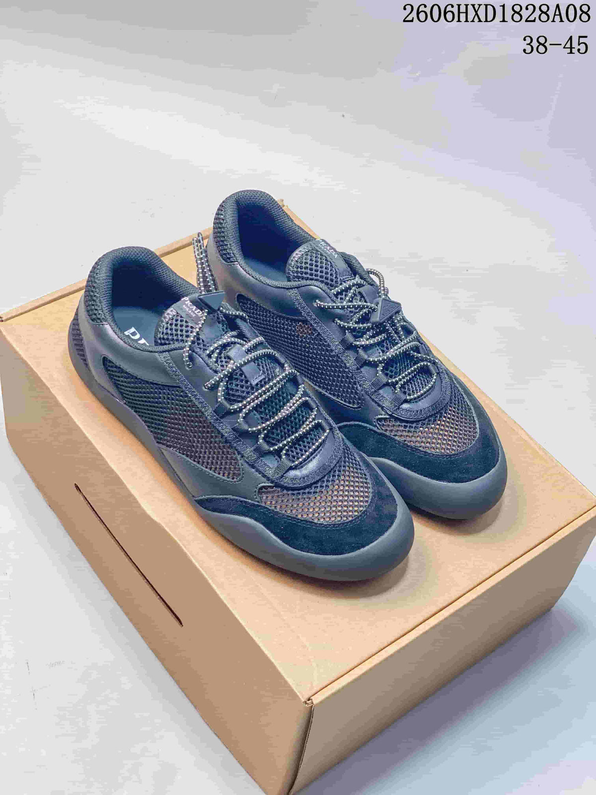 Pair of dark blue Prada-branded mesh sneakers with patterned laces and chunky soles.