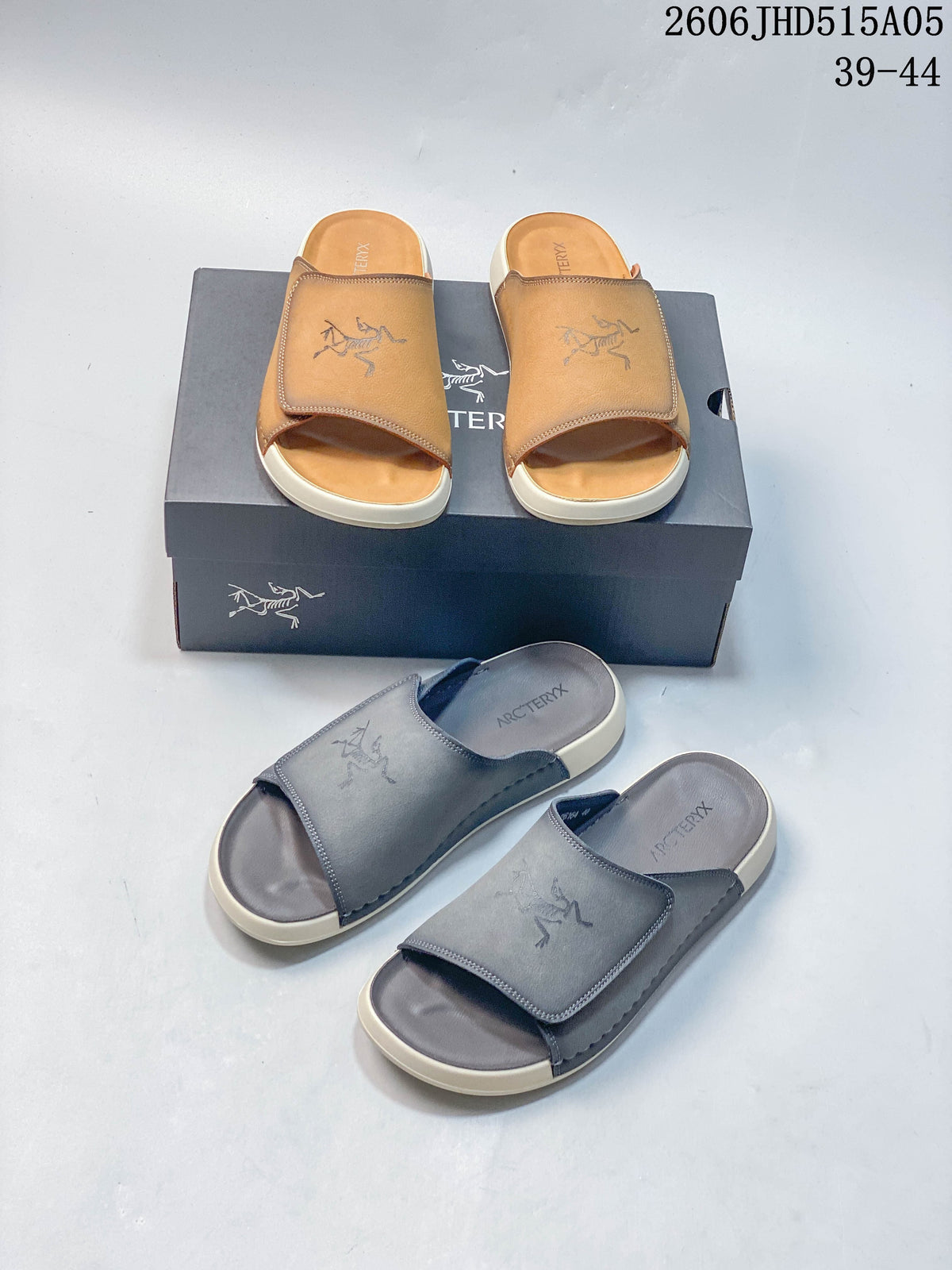 Tan and gray open-toe slide sandals arranged together on and in front of a box.