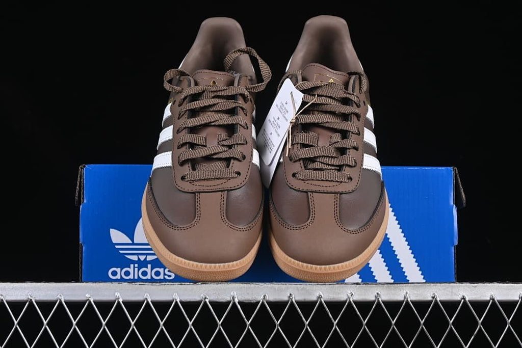 Front view of the pair of brown sneakers resting on a blue adidas box