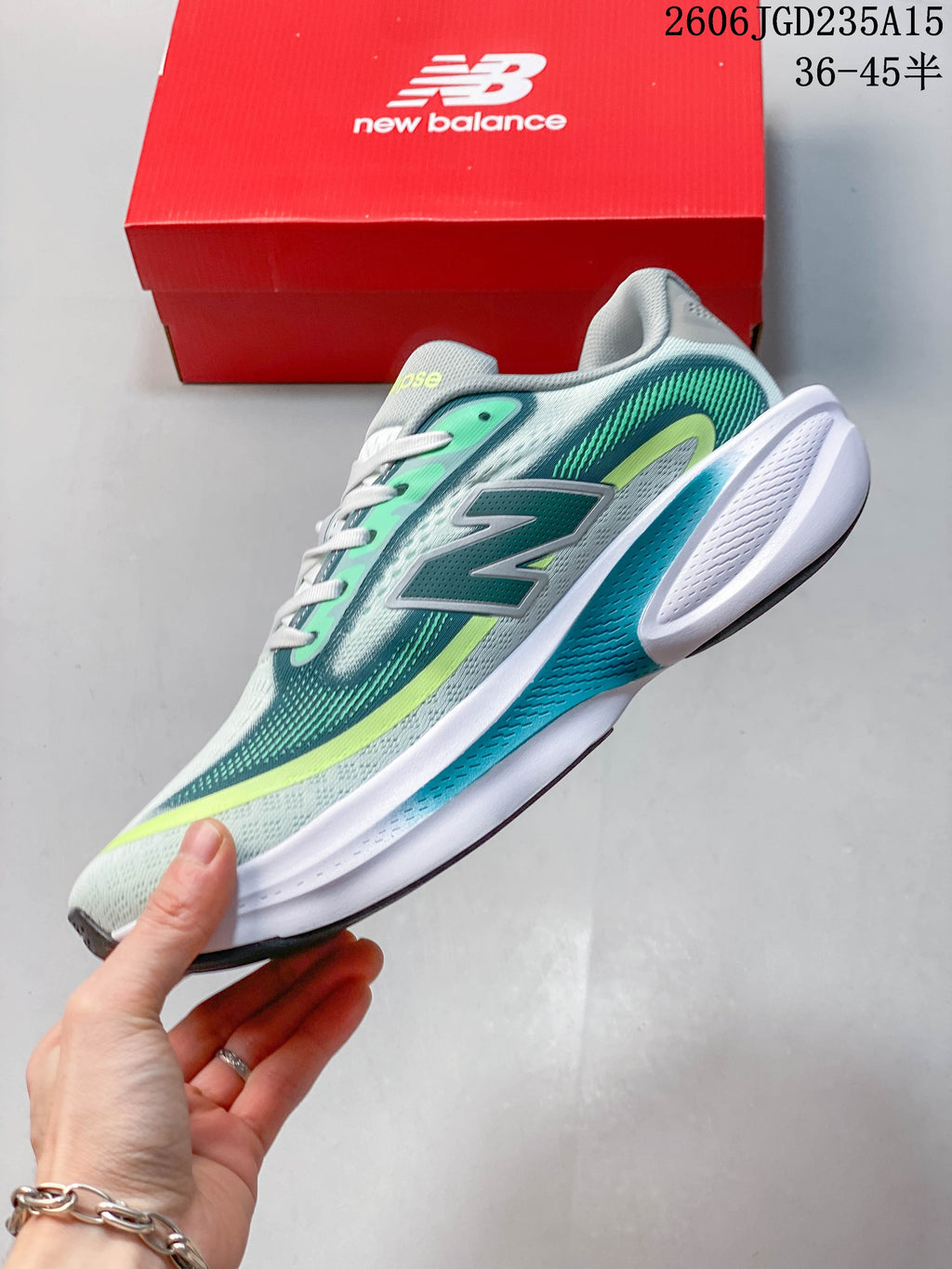 Side view of a pale gray New Balance Ellipse shoe with teal and lime accents.